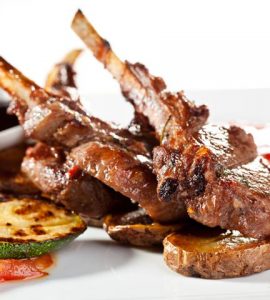 Roasted Lamb Chops on Potato with Tomato and Zucchini Garnished with Sauce